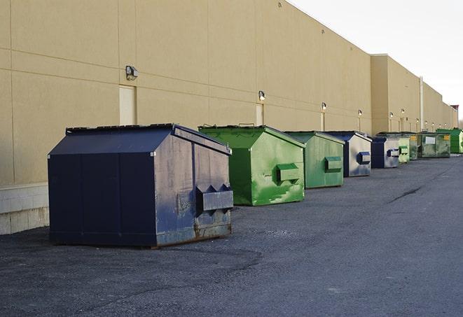 a construction worker unloading debris into a blue dumpster in Berwyn